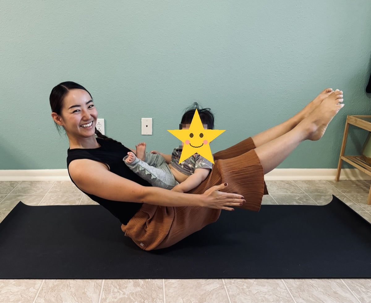 Nagisa doing boat pose with baby on yoga mat - ONE OM ONE